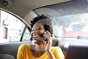 Laughing young woman in a car talking on mobile phone