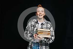 Laughing young woman college student holding books and looking at camera