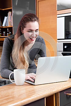 Laughing young woman with computer to telecommute or buy online