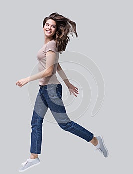 Laughing young woman running, having fun and enjoying life, beautiful joyful girl looking up full length portrait