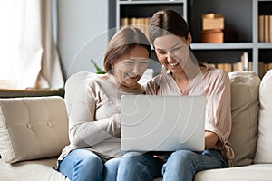 Laughing young woman showing funny video to elderly mommy.