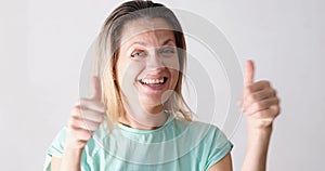 Laughing young woman showing thumbs up