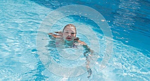 Laughing young woman is swimming in the pool. Concept rest, summer, relaxation