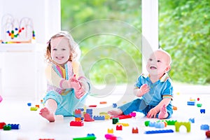 Laughings brother and sister playing with colorful block