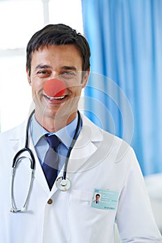 Laughter is the best medicine. Portrait of a handsome smiling young doctor wearing a red clown nose.