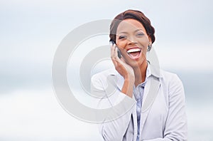 Laughter in the ocean breeze. A pretty african american woman having an enjoyable conversation while outdoors.