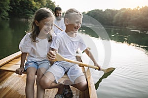 Lauging boy and girl paddling canoe with their father