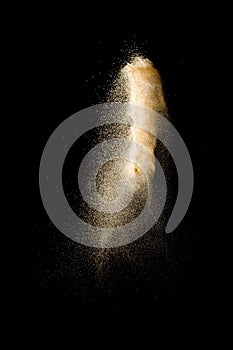 Launch brown particles exploding on black background. Brown dust splashing