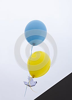 launch a paper dove of peace tied to two yellow-blue balloons