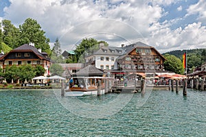 Launch with tourists mooring to wooden pier in lake Konigssee