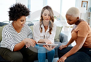 Launching their business into the global market. a group of businesswomen working together on a digital tablet in an