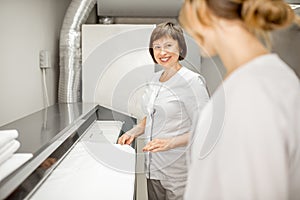 Laundress working with ironing machine