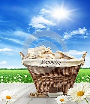 Laundry basket with clothes on rustic table against blue sky