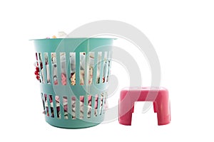 Laundry basket full of clothes and red plastic chair on white