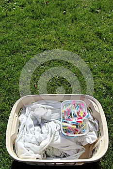 Laundry basket full of laundry ready to be hung out with colourful clothes pegs