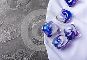 Laundry capsules and a snow-white towel on a black marble background. Laundry detergent for washing clothes in a washing machine.