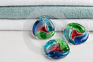 Laundry capsules and towels on white table