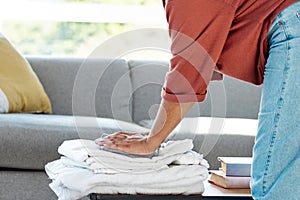 Laundry, chores and hands of a woman with clothes, clean towels and clothing from the wash in the living room. Working