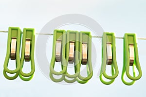 Laundry clothespins of green plastic, with metal clamps. hanging on clothesline rope on open air. selective focus