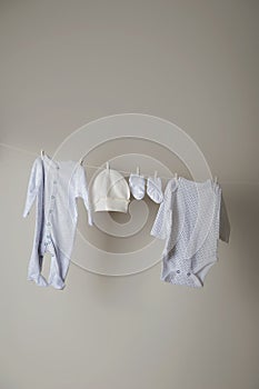 Laundry concept. Cleanliness, ironing, washing of children`s clothes. Baby things dry on a rope close-up and copy space on a gray