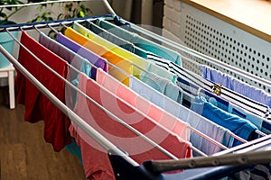 Laundry day Rainbow color clothes hanging on washing line to dry indoors home