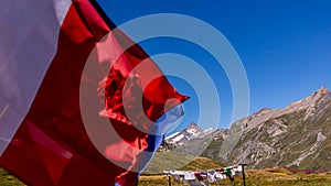 Laundry and flags in mountains. Clothes hanging to dry, flags waving in wind and blue sky in summer in Aosta Valley in Italy