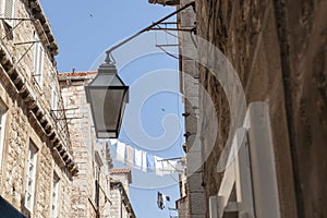 Laundry hanging high above the street between two old stone apartment buildings in European city