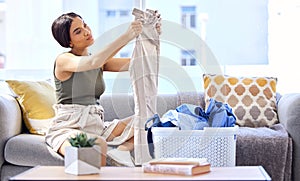 Laundry, housekeeping and woman folding clothes, cleaning and working in the living room of her house. Routine, washing