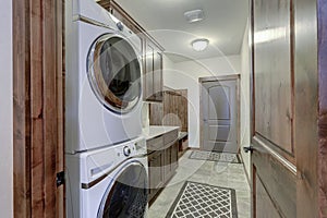 Laundry room interior with white washer and dryer and rich dark wood cabinets and doors