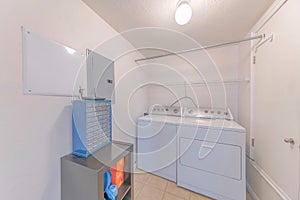 Laundry room with washing and drying machines, racks on the white wall, shelf and a blue organizer