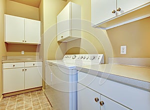 Laundry room with white cabinets and yellow walls.