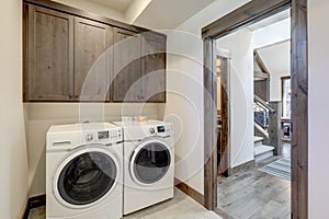 Laundry room with white wahser and dryer and dark brown wood cabinets