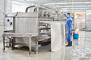 Laundry worker in the process of working on automatic machine for carpet washing