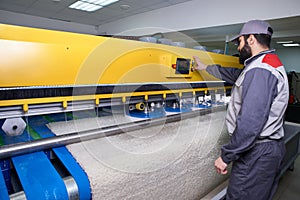 Laundry worker in the process of working on automatic machine for carpet washing in dry cleaning