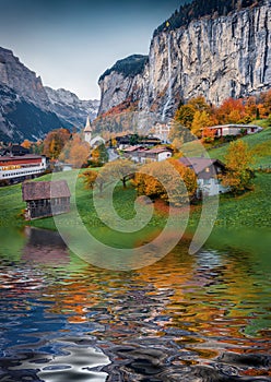 Lauterbrunnen village reflected in the calm waters of small lake. Impressive rural scene of Swiss Alps