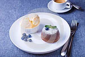 Lava cake - chocolate fondant cake with vanilla ice cream, blueberries, mint and coffee. Traditional French pastries. Close-up