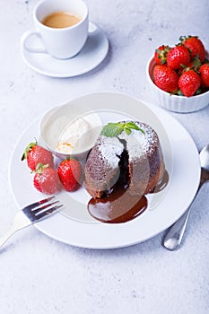 Lava cake - chocolate fondant cake with vanilla ice cream, strawberries, mint and coffee. Traditional French pastries. Close-up
