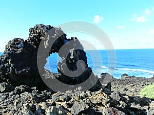 Lava concretions in front of a blue ocean.