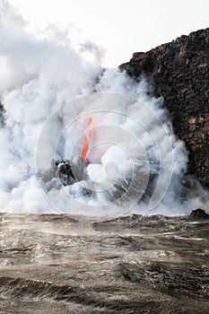 Lava flowing into ocean with steam and smoke