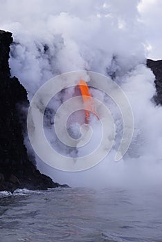 Lava flowing out of cliff into the ocean surounded by white cloud steam