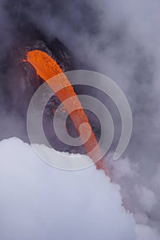 Lava flowing out of cliff suround with white cloud steam