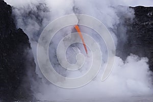 Lava flowing out of cliff suround with white cloud steam