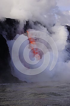 Lava flowing out of cliff suround with white cloud steam