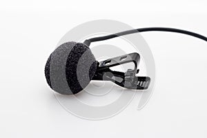 Lavalier or lapel microphone on a white surface, very close-up. The details of the grip clip or bra and the sponge against the photo