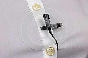 The lavalier microphone is secured with a clip on a womens shirt close-up. Audio recording of the sound of the voice on a