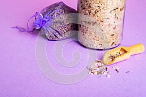 Lavender bath salt with spoon and dried lavender on purple background.