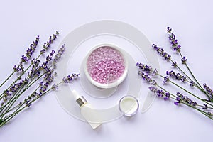 Lavender blossom, sea salt, cream jar and essential oil on white background, top view, flat lay