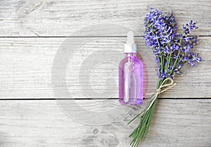 Lavender bouquet and oil bottle top view on wooden background empty copy space. Aromatherapy,spa and relax. Cosmetics ingredient