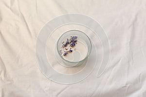 Lavender candles with fresh lavender on a white fabric background with space for text