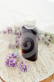 Lavender essential oil bottle on white wooden rustic board with fresh lavender flowers. Aromatherapy treatment, natural organic